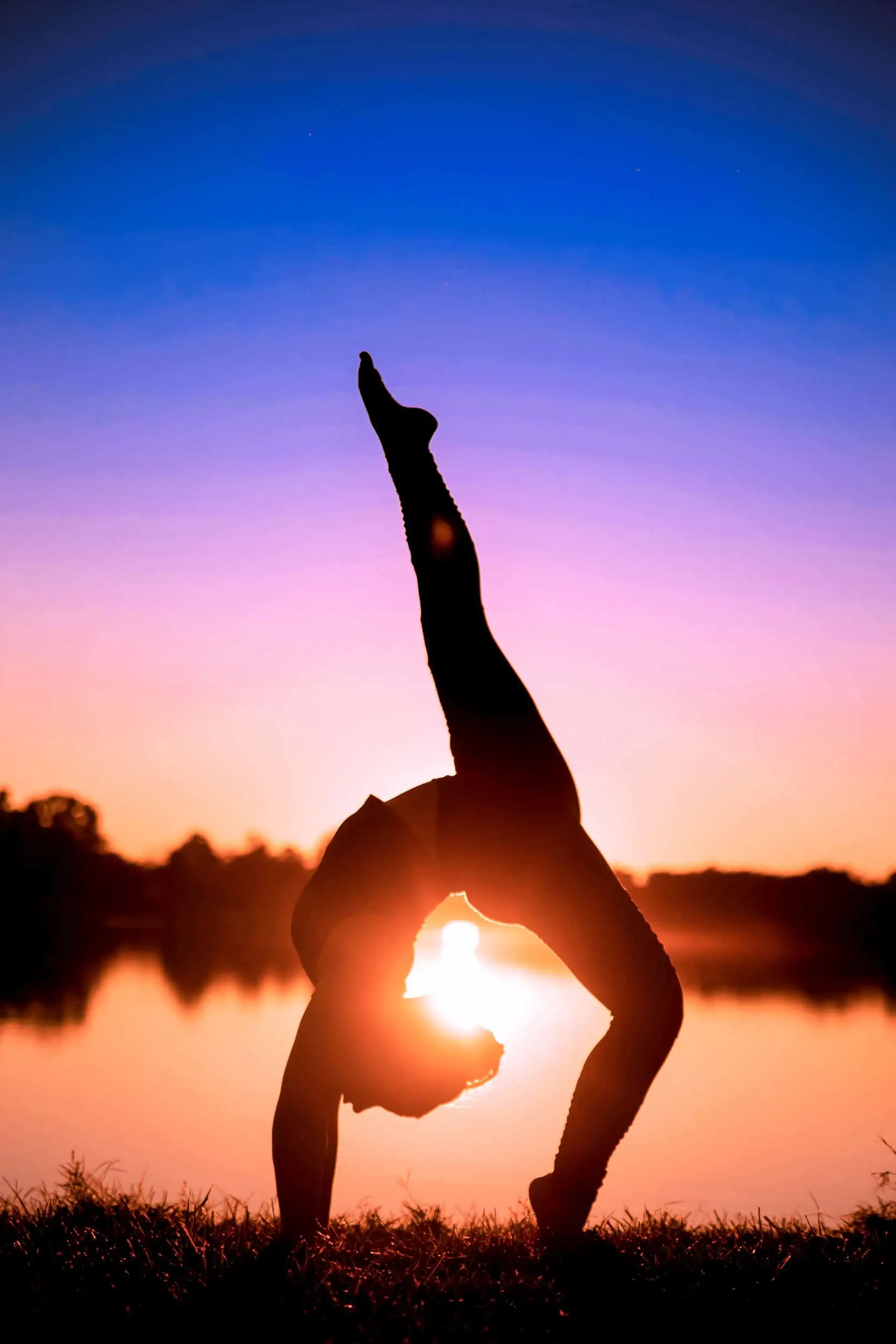 A silhouette of a woman doing yoga at sunset.