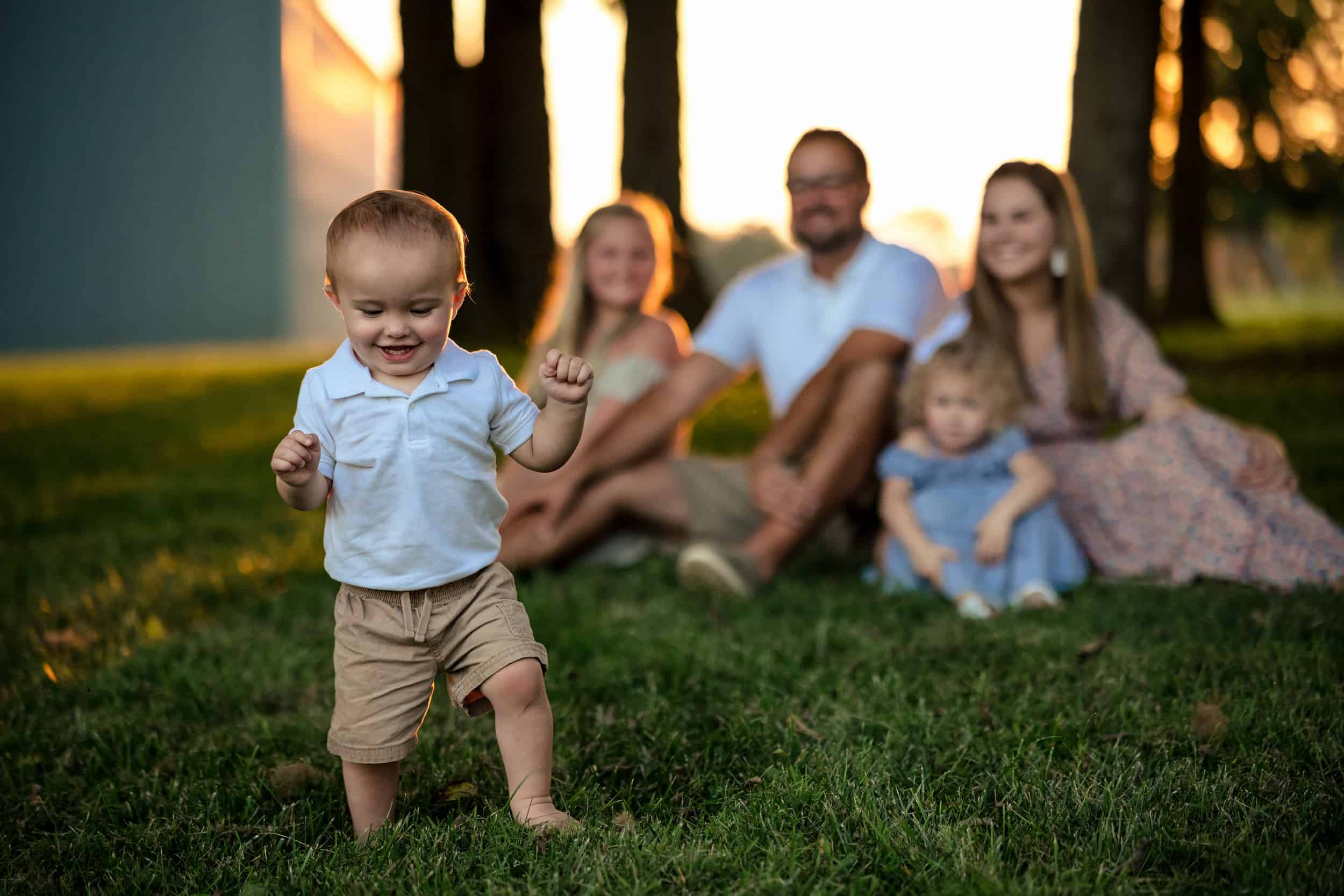 A family sits on a grassy field at sunset.