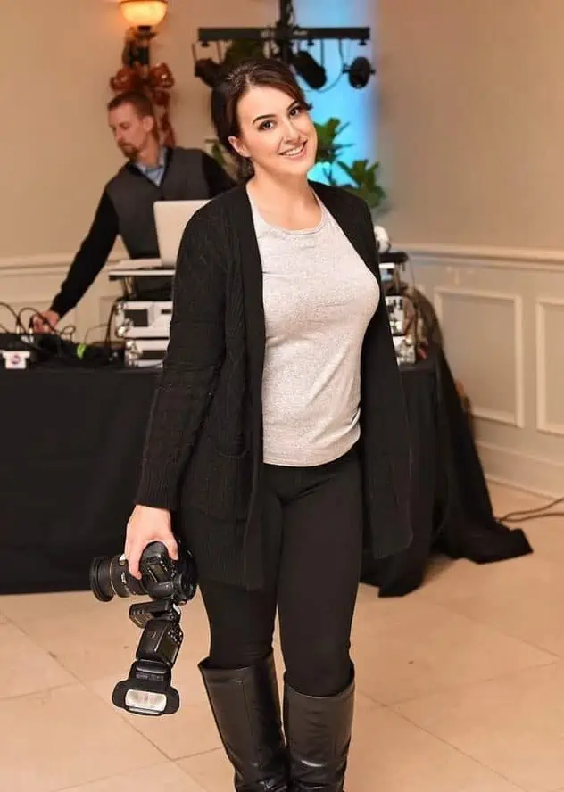 A woman with a camera posing in front of a group of people.