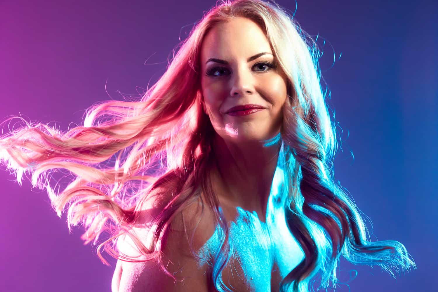 A woman with long blonde hair posing for a headshot in front of a colorful background at a photography studio in Lexington, KY.