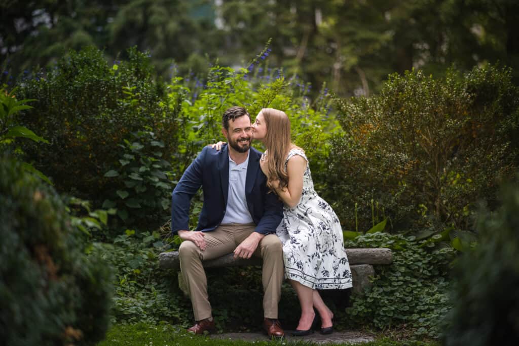 A couple embracing on a bench in a picturesque Frankfort KY garden during their engagement photoshoot.