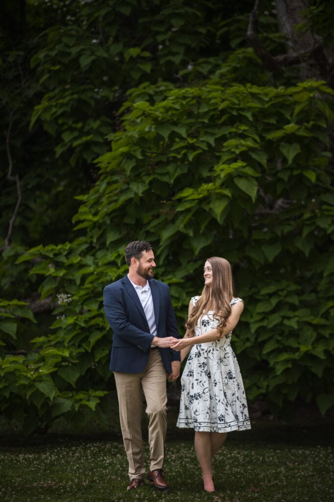 An engaged couple holding hands in front of a tree during their Frankfort KY engagement photos.
