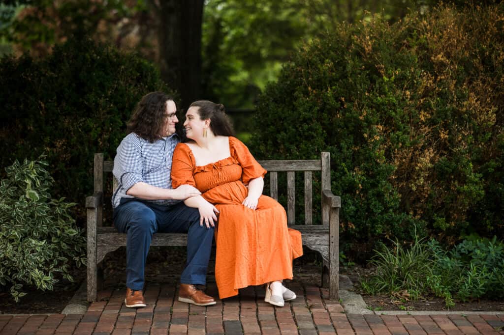 A couple enjoys their engagement session at UK Arboretum, sitting on a bench in the park.
