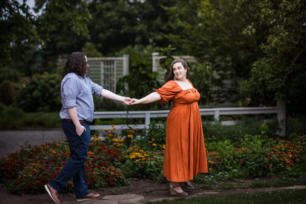 A couple's engagement session at the UK Arboretum, holding hands in a garden.