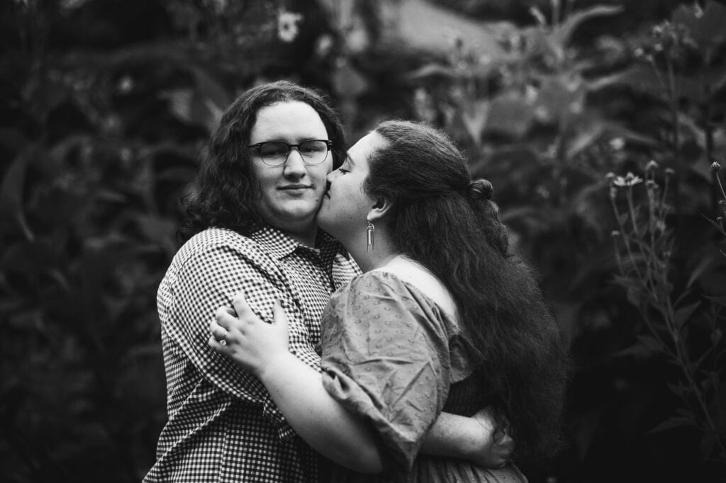 Engagement session photo of couple hugging amidst UK Arboretum's bushes.