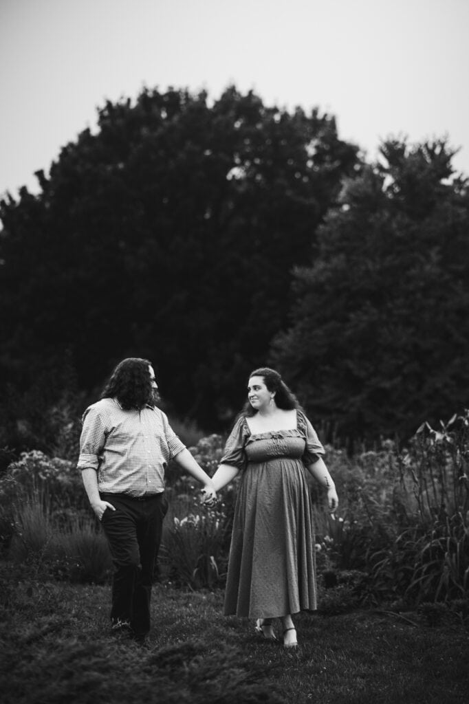 An engagement session at UK Arboretum captured in black and white, featuring a couple walking through a garden.