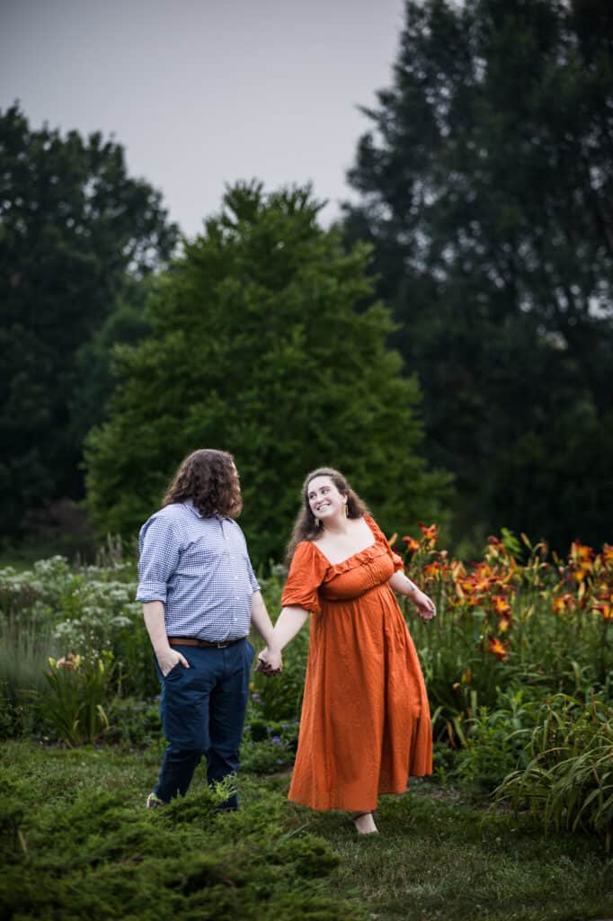 A couple's engagement session at UK Arboretum, where they hold hands in a field of flowers.