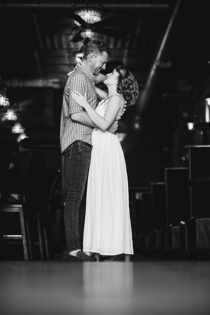 A black and white engagement session photo of a couple embracing at Bourbon on Rye.
