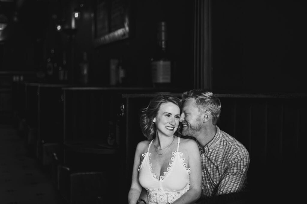 An engagement session photo of a couple sitting at Bourbon on Rye.