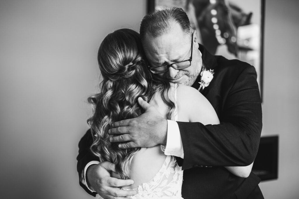A black and white photo of a bride hugging her father at the Harper Hall Wedding.