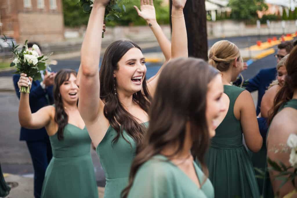 A group of bridesmaids at a Harper Hall wedding, with their hands in the air.