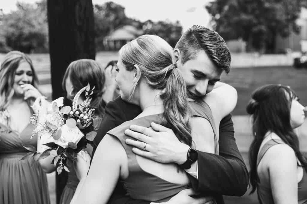 A Harper Hall Wedding captured in a black and white photo, featuring a bride hugging her bridesmaids.