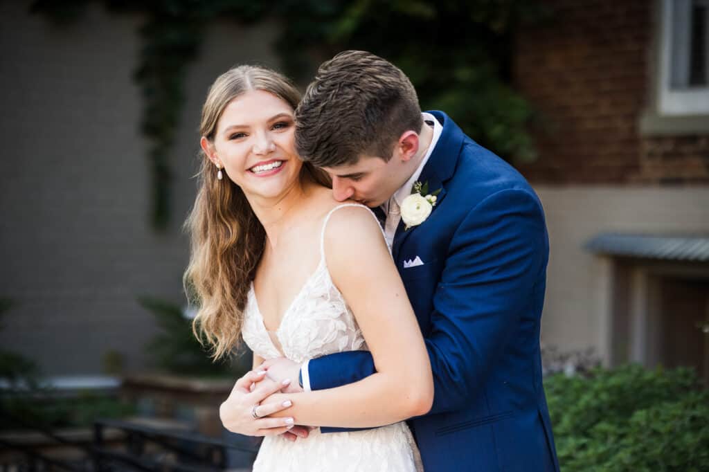 A Harper Hall wedding with a bride and groom hugging in front of a brick building.