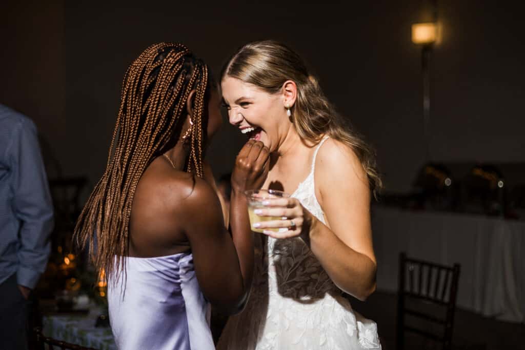 Two brides laughing at each other at a Harper Hall wedding reception.