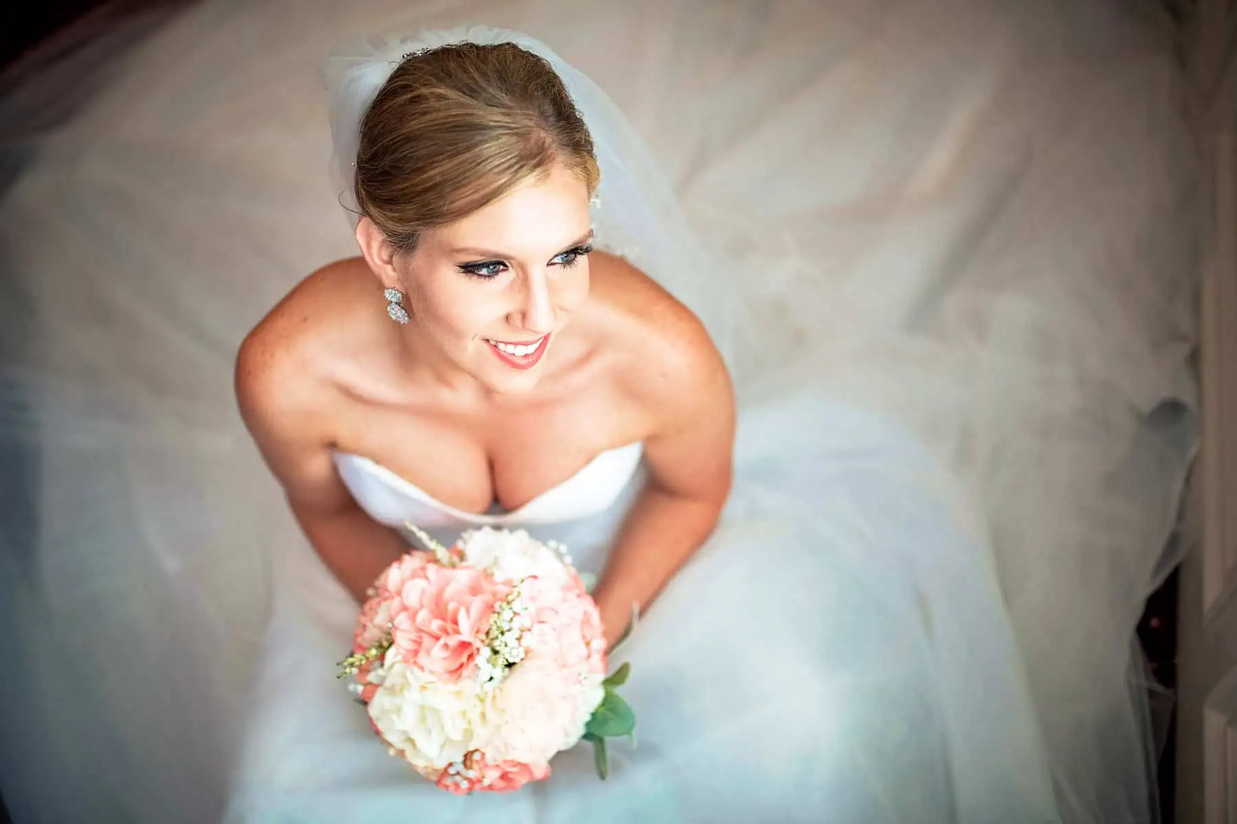 A bride in a wedding dress posing with her bouquet.
