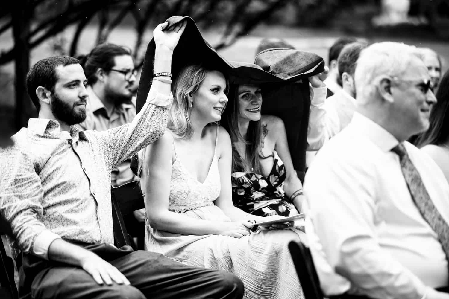 Black and white photo of a wedding ceremony with a woman wearing a hat.