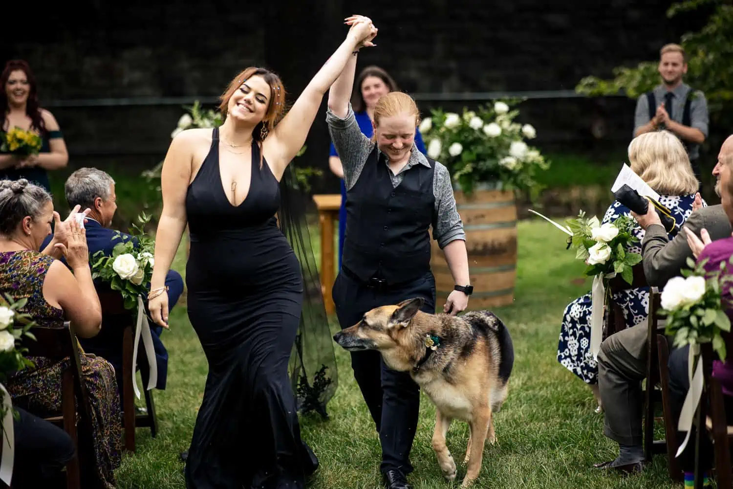 A bride and groom walking down the aisle with a dog.