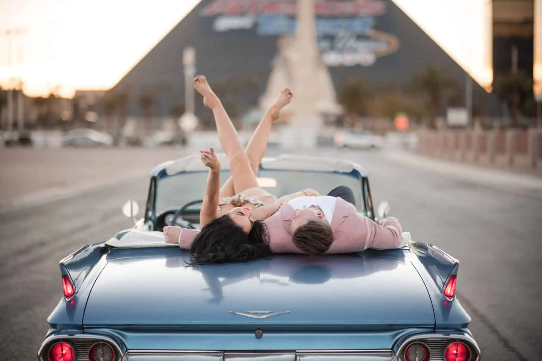 A couple laying on top of a classic car in las vegas.