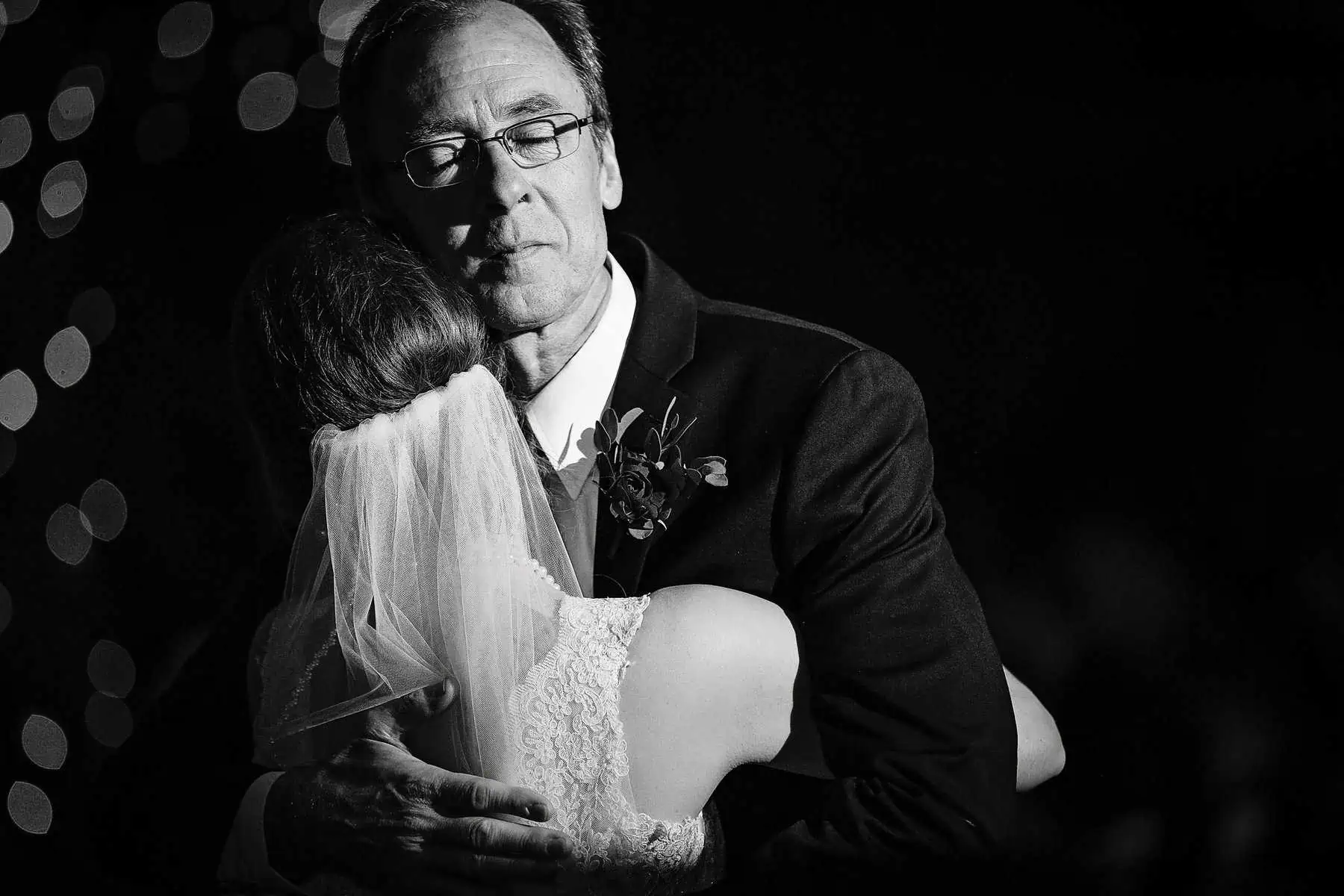 A black and white photo of a bride hugging her father.