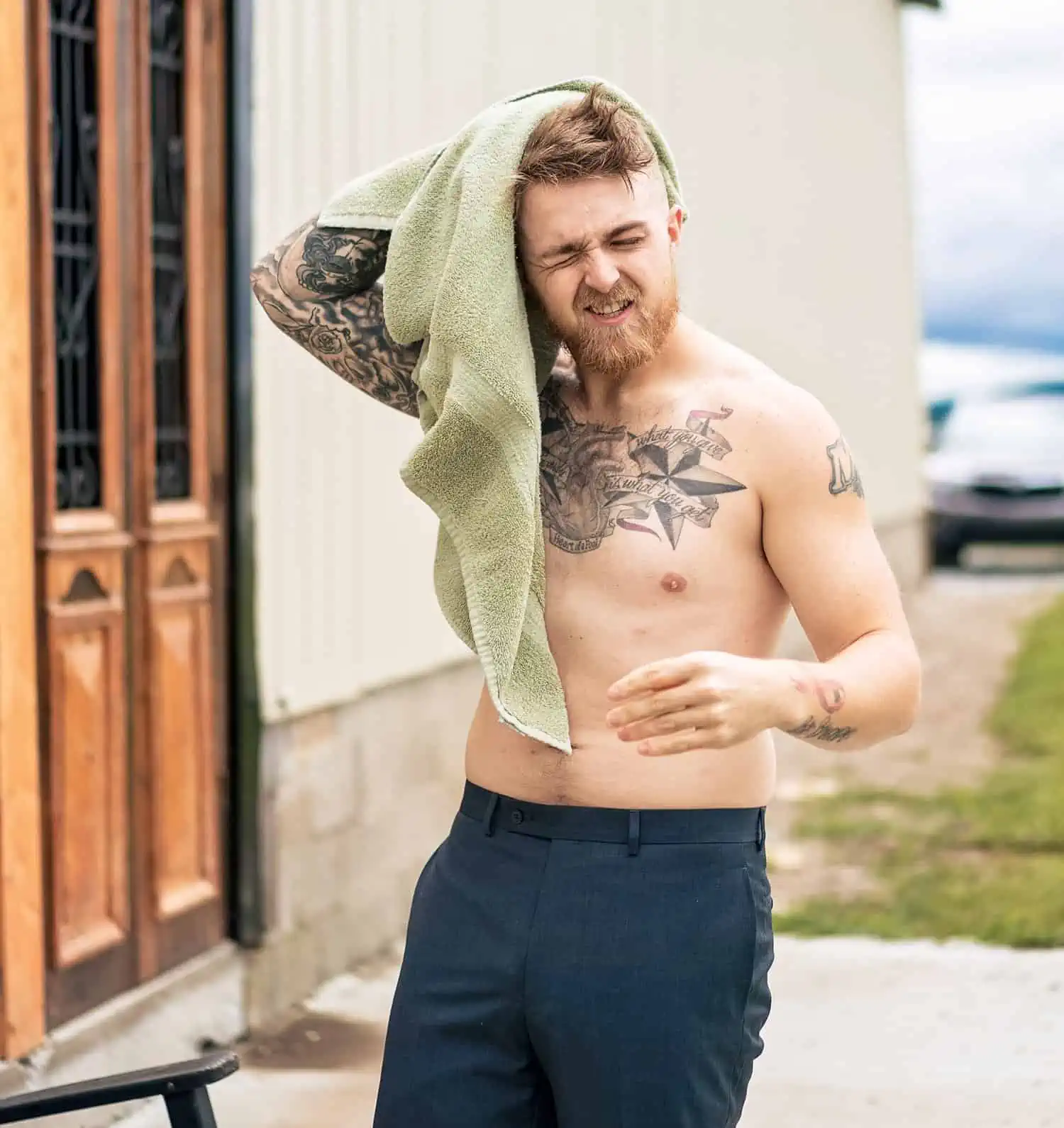 A man with tattoos is drying his hair with a towel.