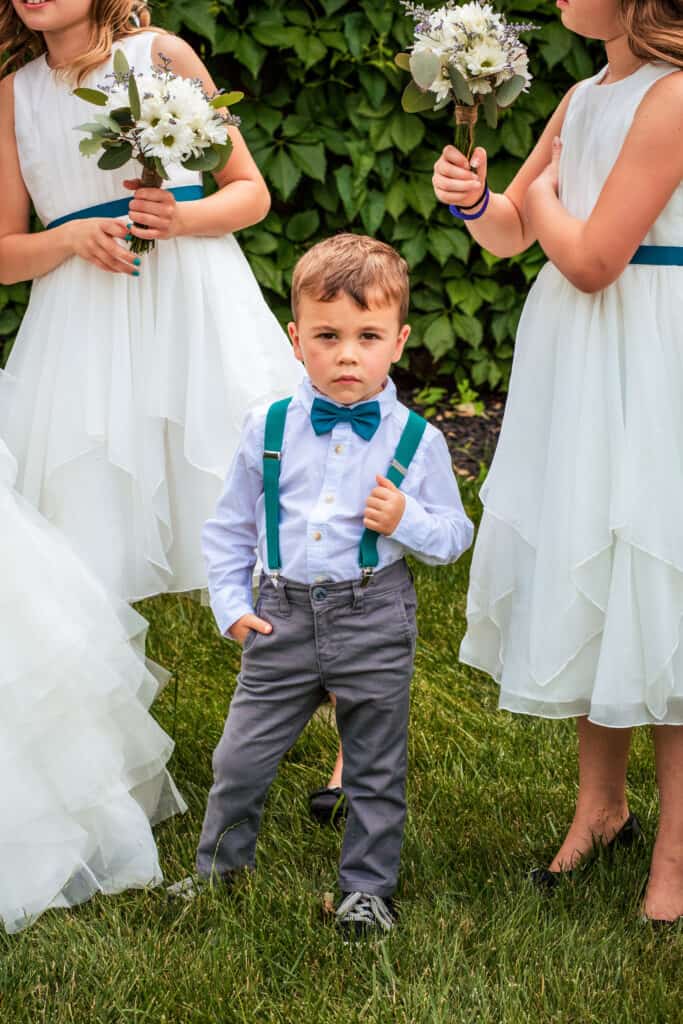A little boy stands next to bridesmaids at a wedding.