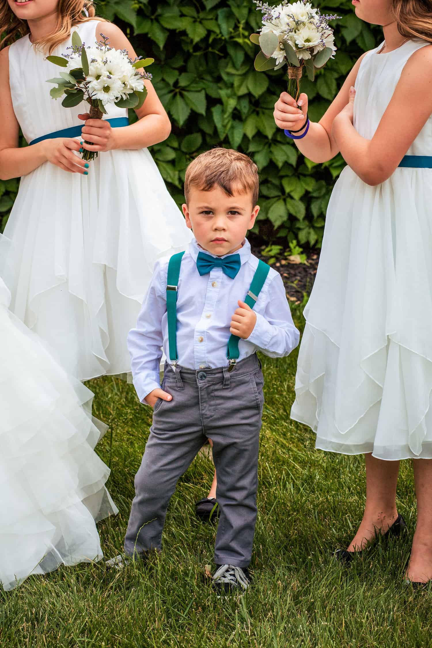 A little boy is standing next to a group of bridesmaids.