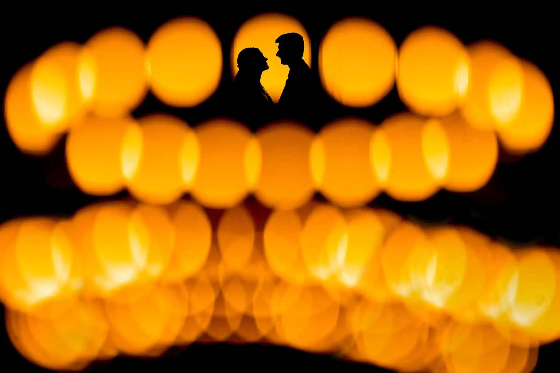 A silhouette of a couple with candles in the background.