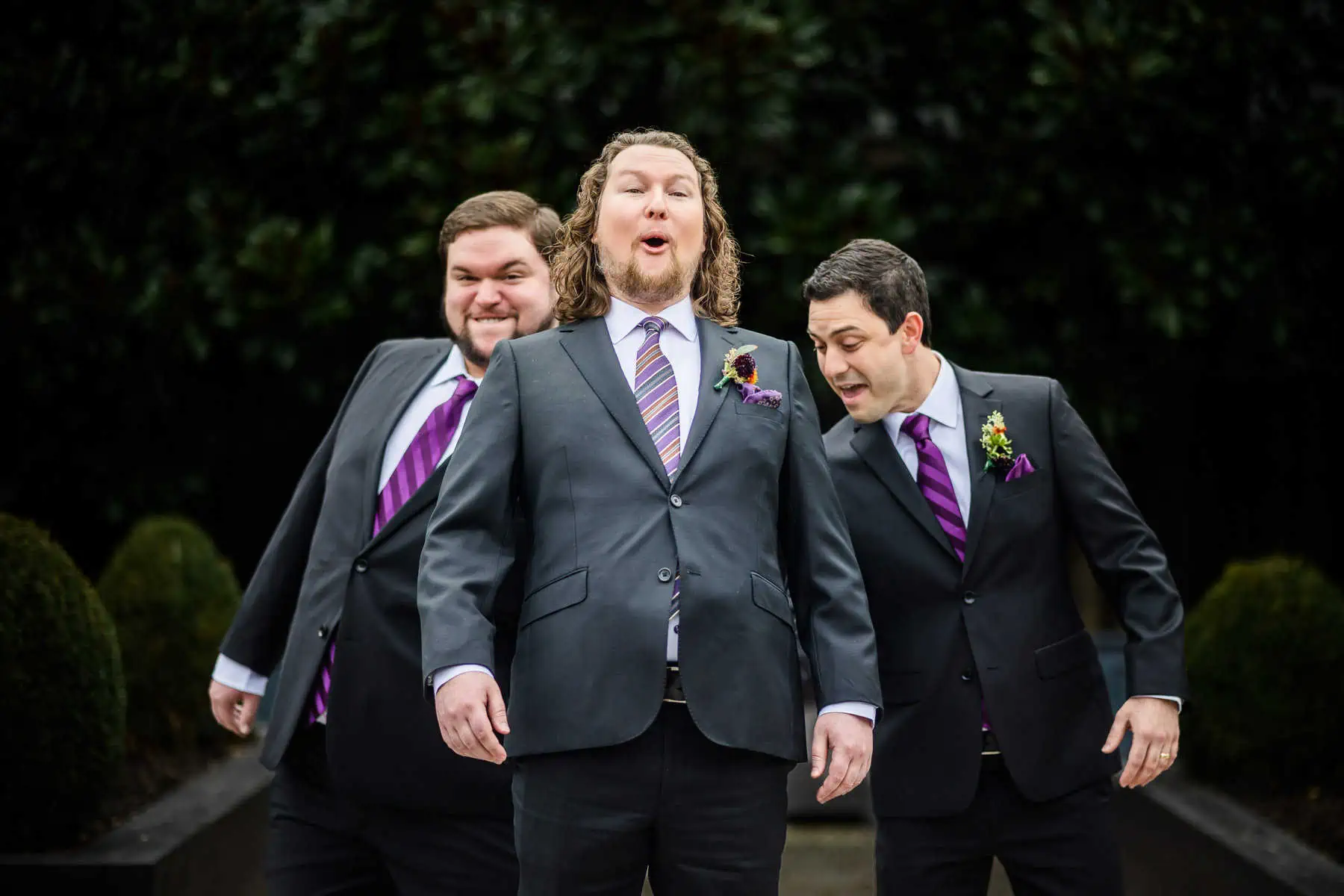 Three groomsmen in suits and ties are posing for a photo.