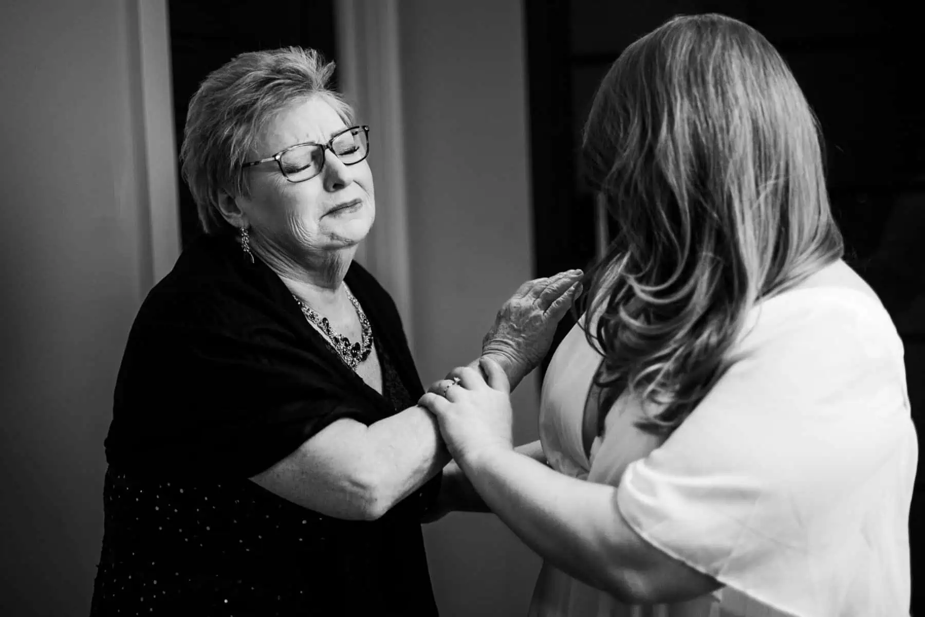 A black and white photo of an older woman helping a younger woman.