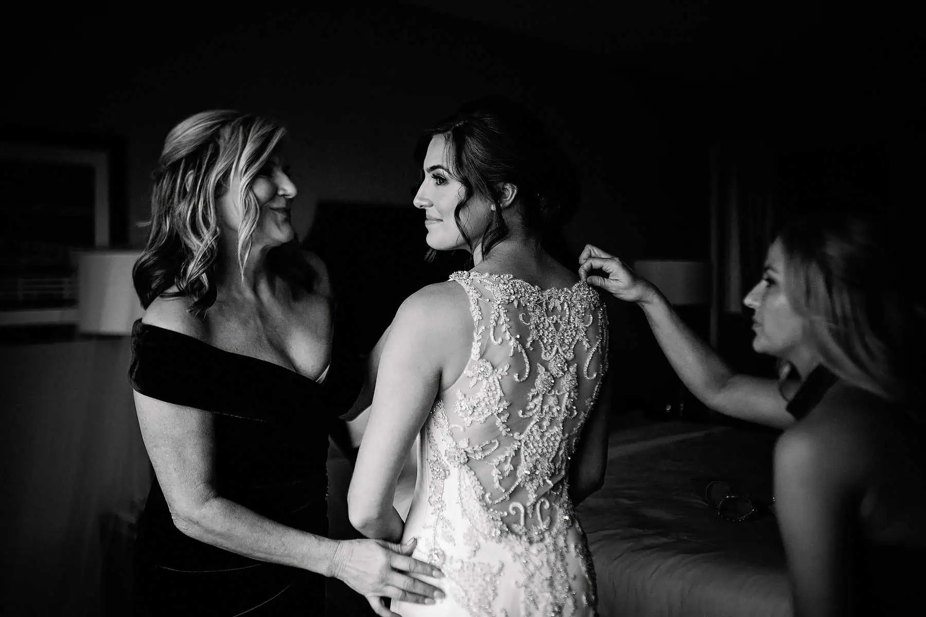 A bride helping her mother put on her wedding dress.