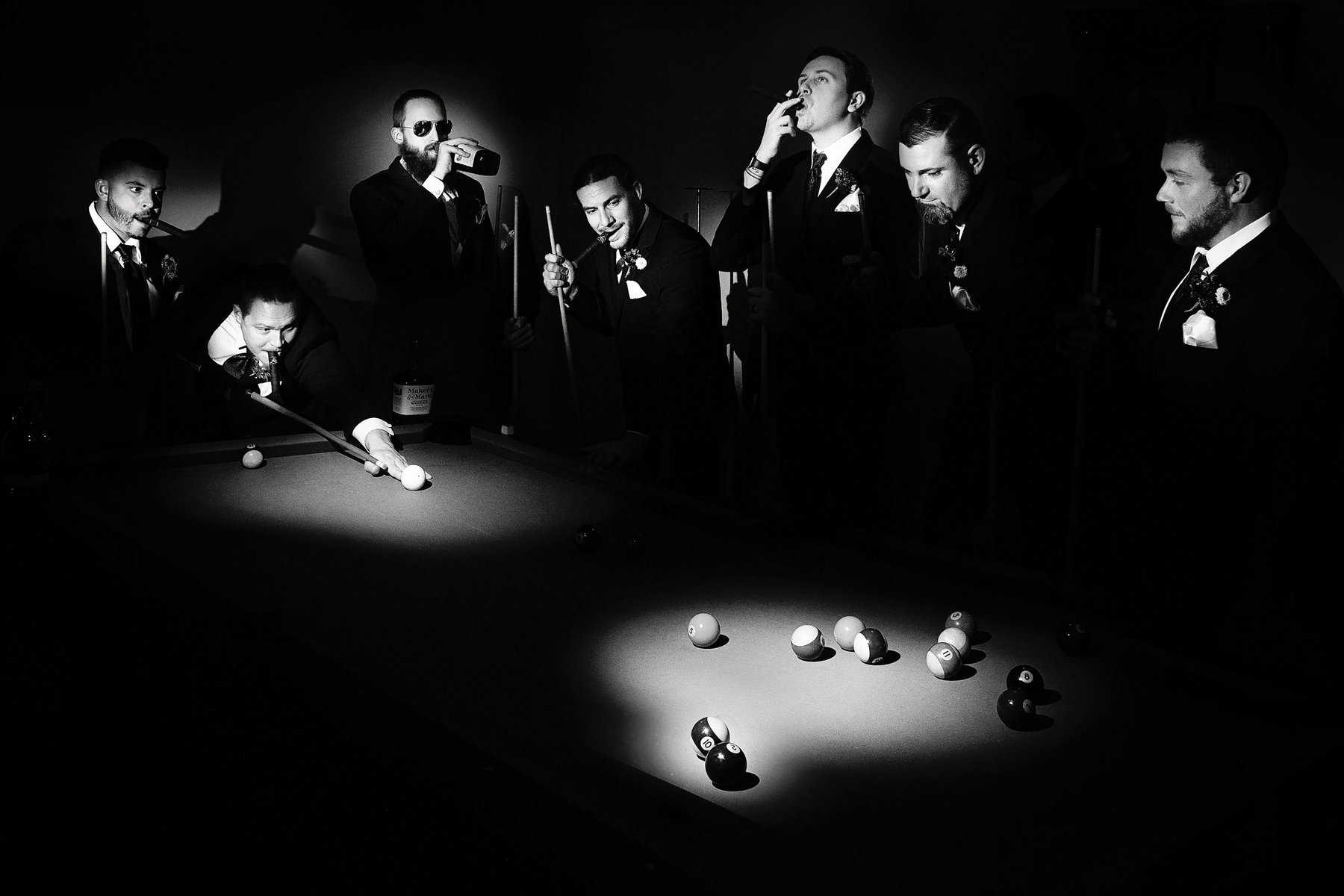 A black and white photo of a group of men playing pool.