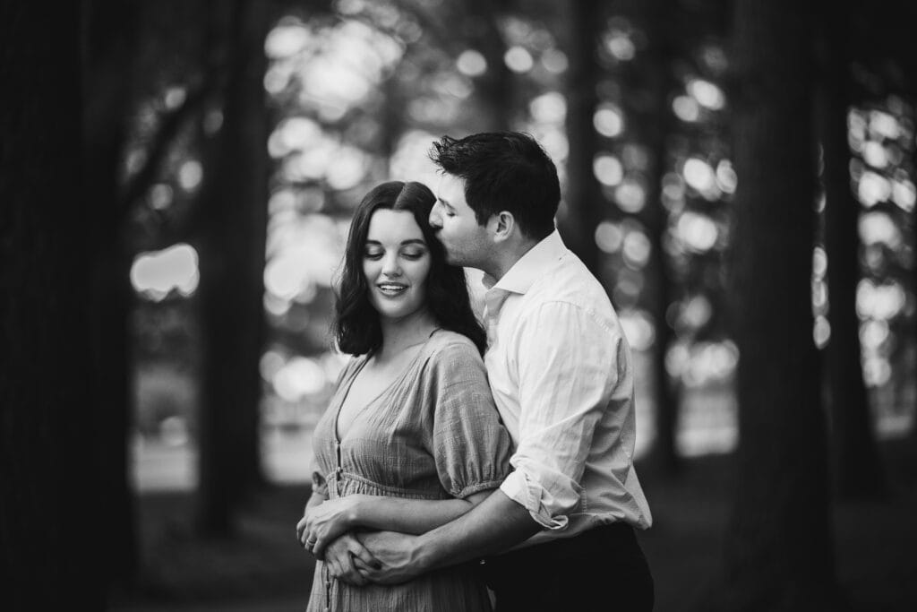 Jacobson Park Engagement Photos: A Black And White Photo Of A Couple Embracing In The Woods.