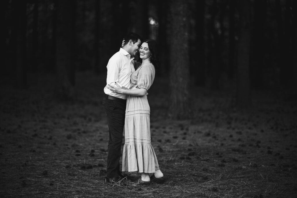 A Black And White Jacobson Park Engagement Photo Of A Couple Embracing In The Woods.