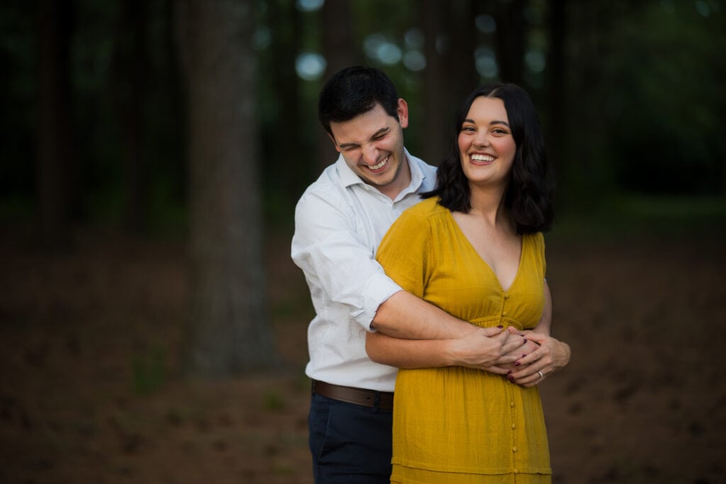 Jacobson Park Engagement Photos - A Couple Embracing In The Woods During Their Engagement Session.