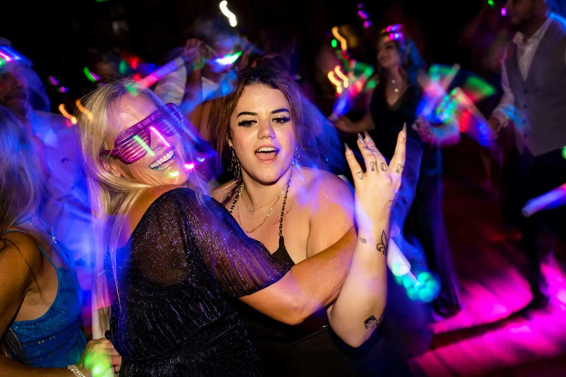 Two women dancing with glow sticks at a party.