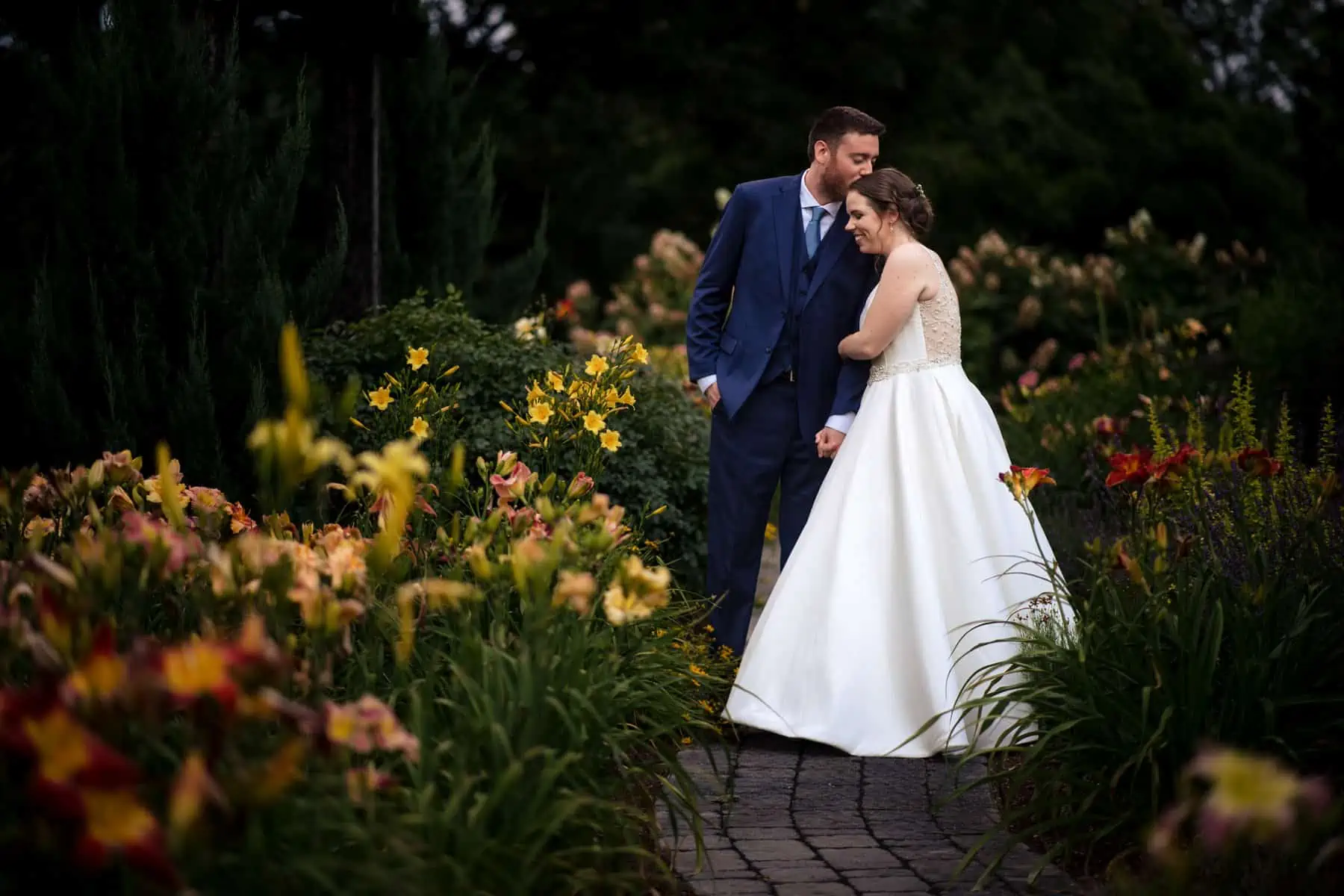 A bride and groom posing in a garden.