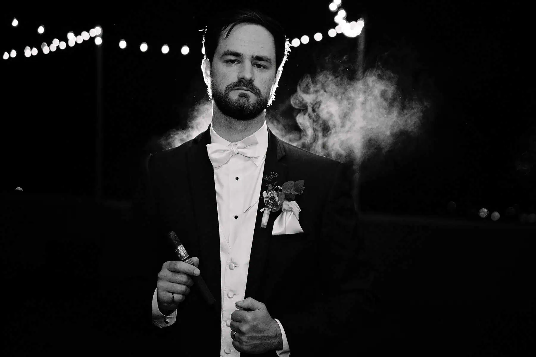 A man in a tuxedo smoking a cigar.
