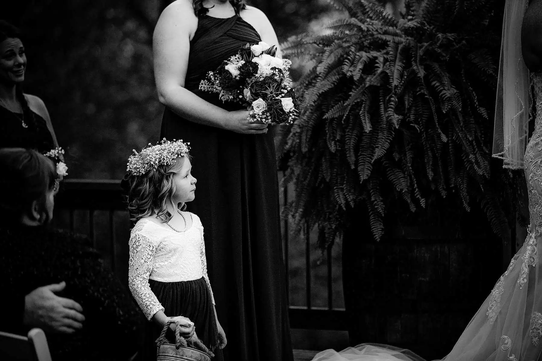 Black and white photo of a little girl at a wedding ceremony.