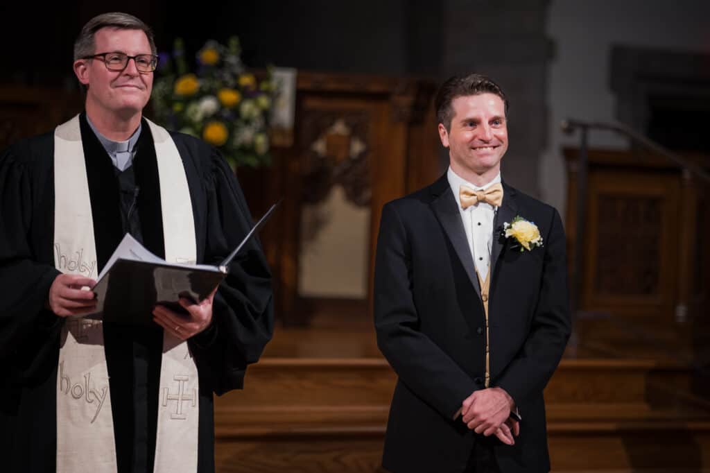 A Man In A Tuxedo Standing Next To A Priest At A Micro Wedding In Lexington, Ky.