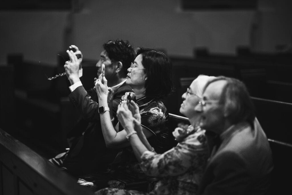 A Black And White Photo Of People Clapping At A Micro Wedding In A Church.
