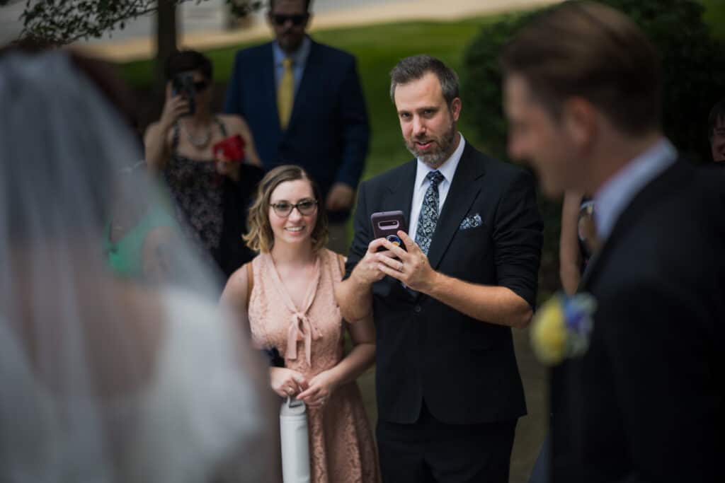 A Man In A Suit Looking At His Cell Phone During A Micro Wedding In Lexington, Ky.