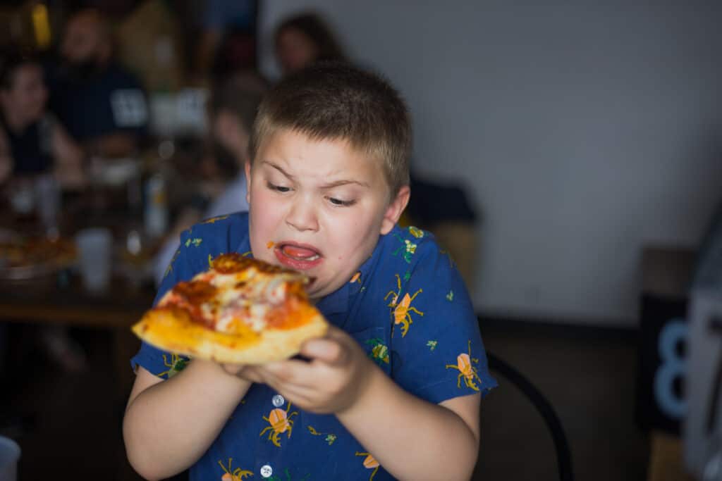 A Boy Eating A Piece Of Pizza At A Micro Wedding In Lexington, Ky.
