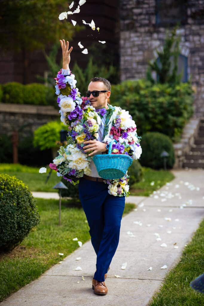 A man walking down a sidewalk with flowers.