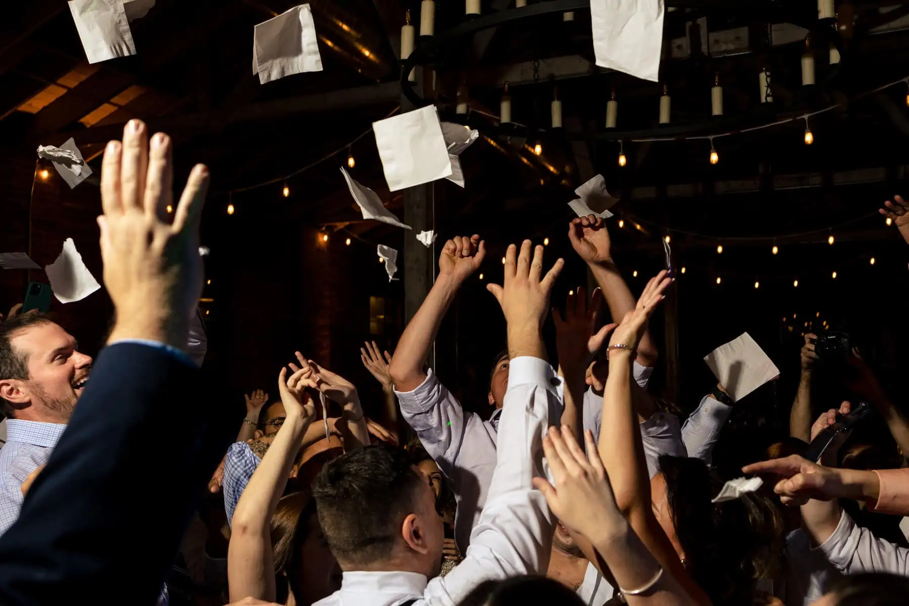 A group of people throwing paper into the air at a wedding reception.