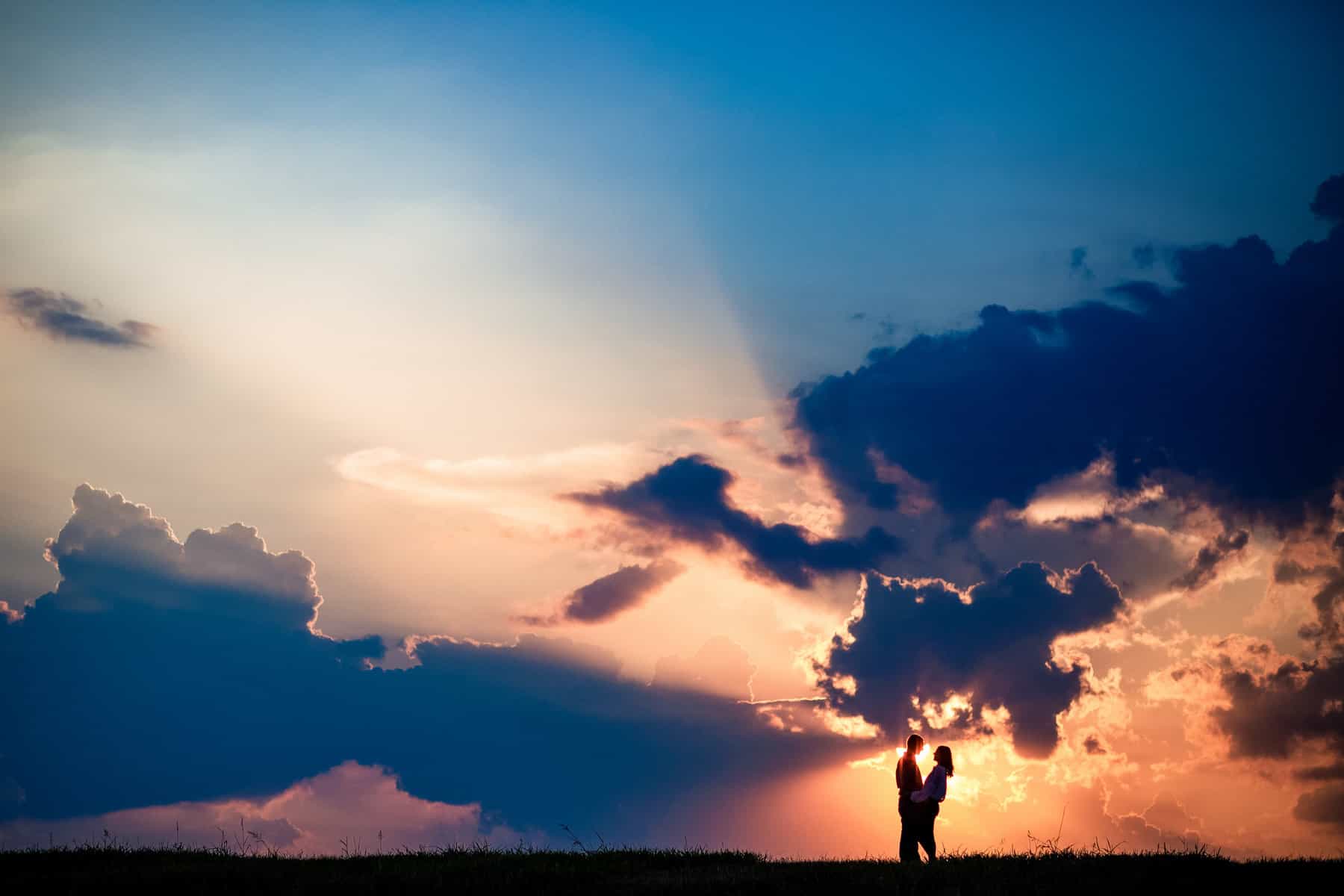 A silhouette of a person standing on a field at sunset.