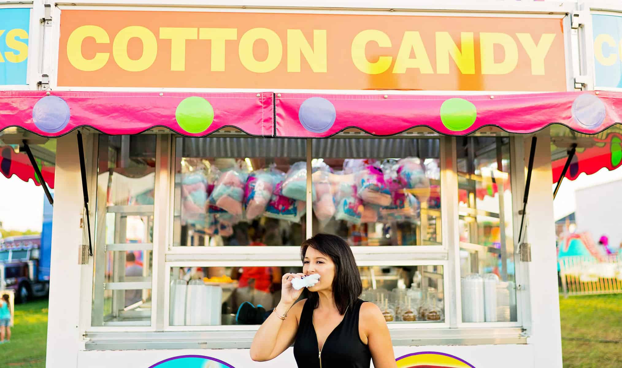 A woman is standing in front of a cotton candy stand.