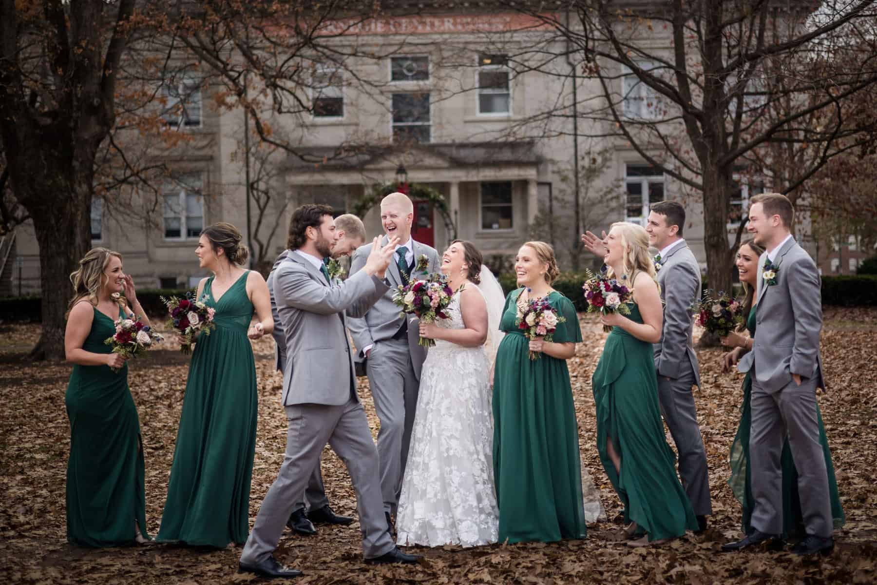 A group of bridesmaids and groomsmen posing in front of a building.