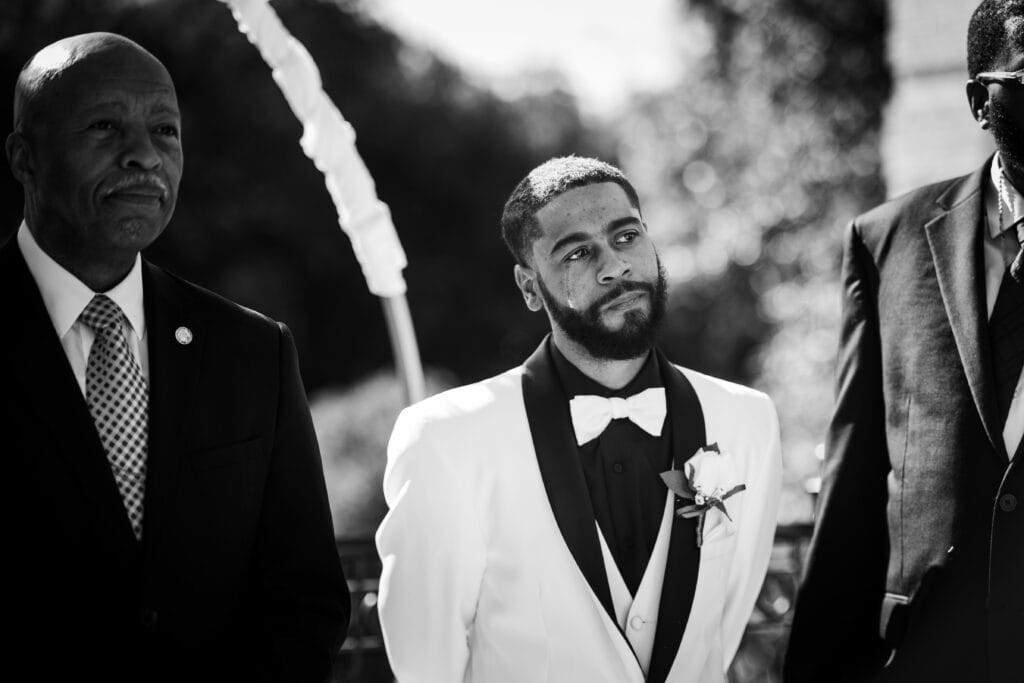 A Man In A Tuxedo Stands Alongside A Man In A Suit, Captured By Skilled Lexington Ky Wedding Photographers.
