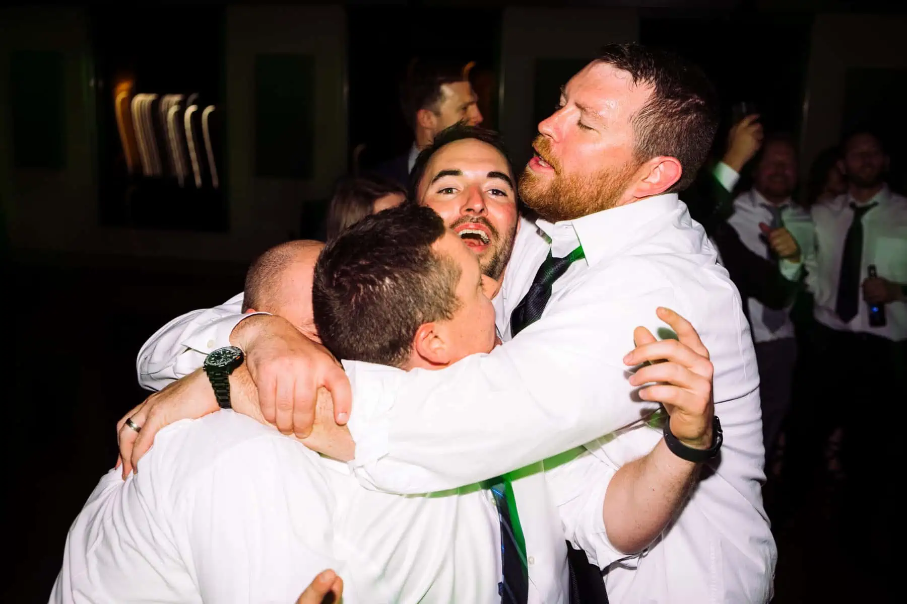 A group of men hugging each other on the dance floor.