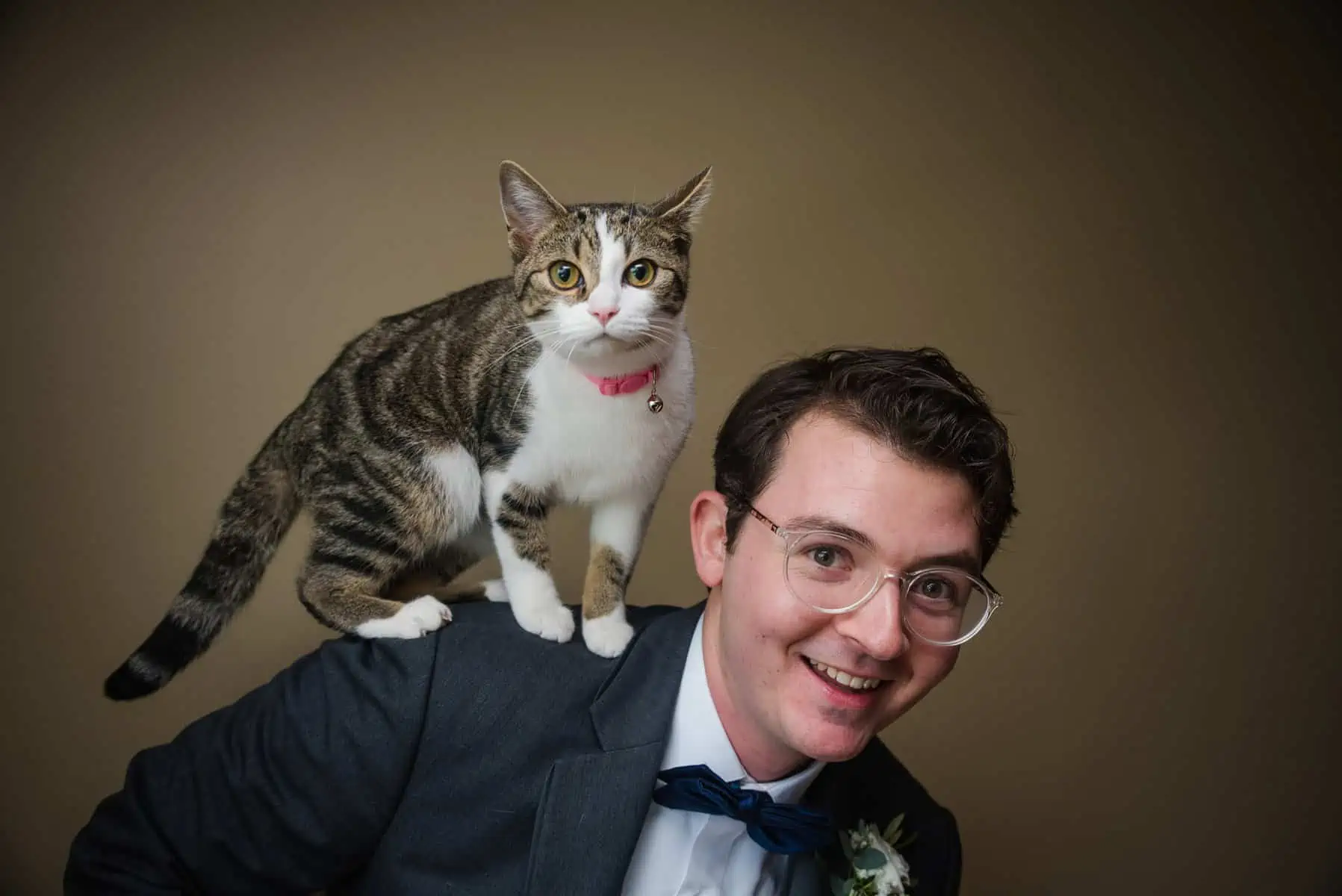 A man wearing a suit with a cat on his shoulder.